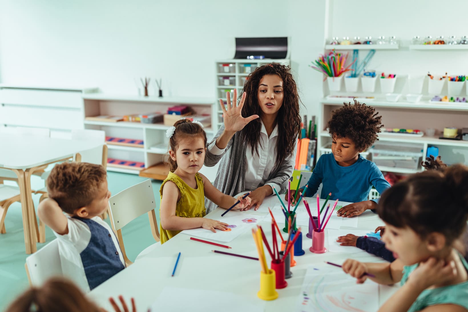 Teacher sitting at a table with children doing art